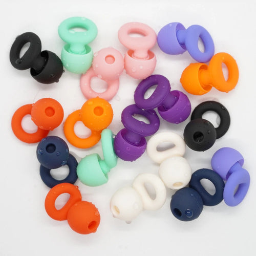 Reusable silicone earplugs and spare tips scattered on a white surface in black, mint, pink, purple, orange, cream and navy